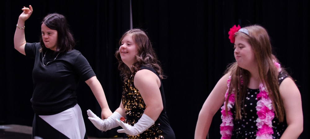 three girls dancing on stage during showcase performance